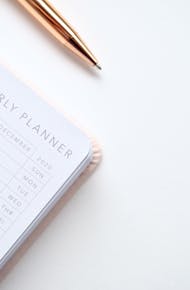 Close-Up Photo of Yearly Planner Beside a Pen